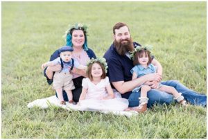 Family of 5 sitting on the grass smiling