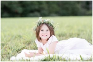 little girl laying down in a field and smiling