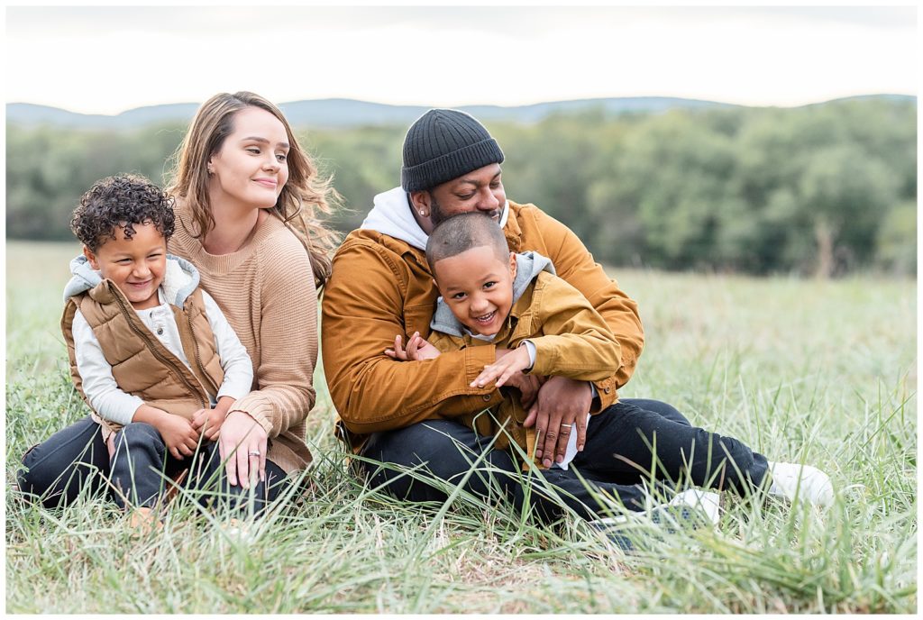 a family of 4 gets cuddly on the grass in a fall family session