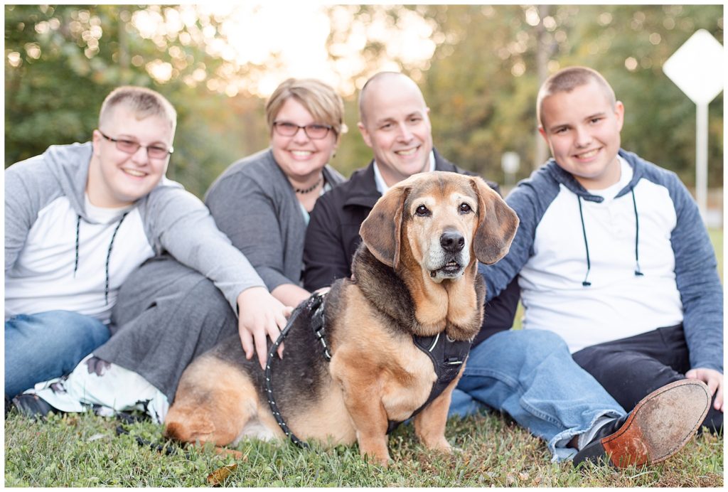 a dog sits in front of his family on the grass