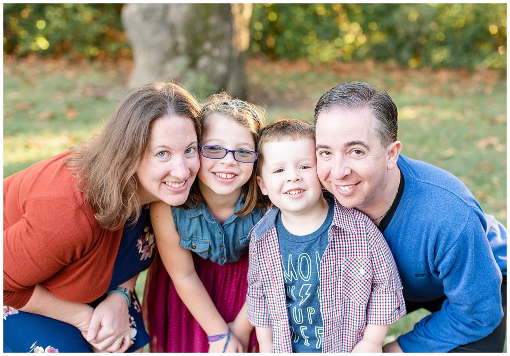 a family of 4 smiles for the camera for baker park fall mini session