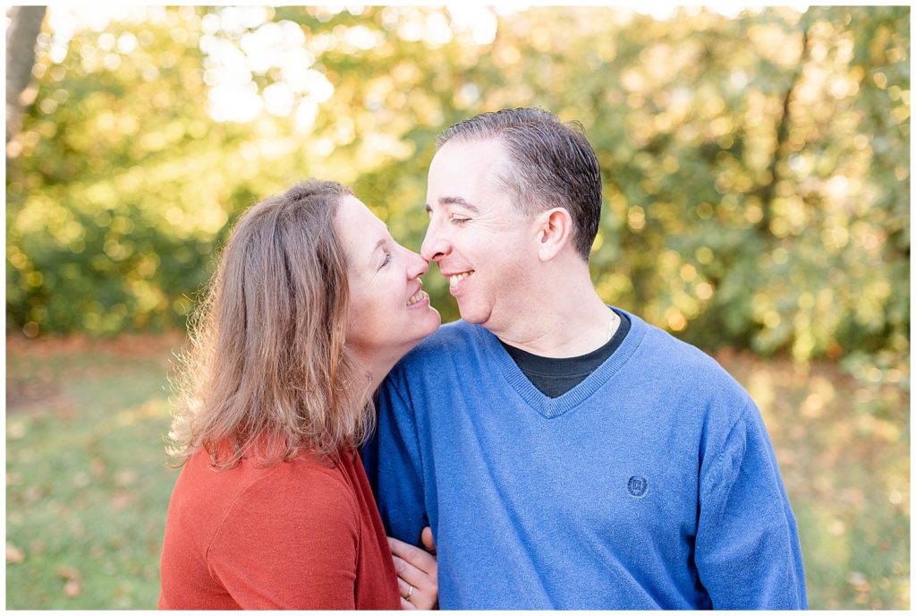 a couple looks at each other and smiles for fall mini session