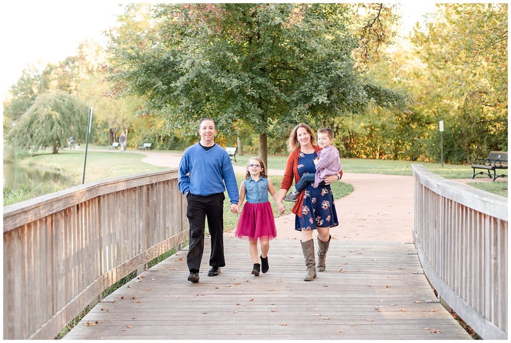 family of 4 walks across a bridge at baker park