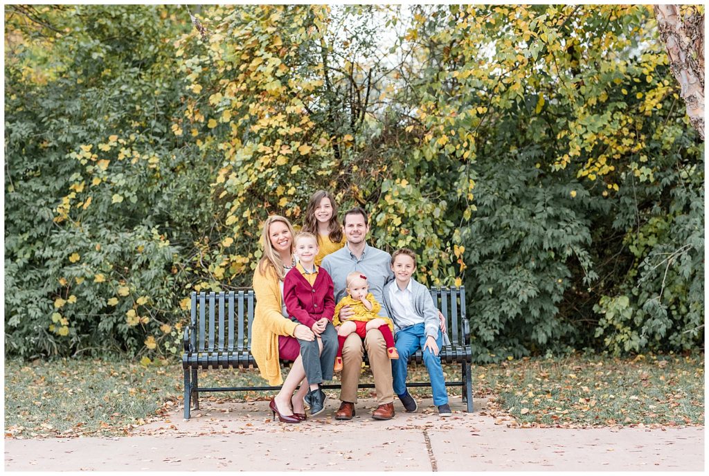 a family of 6 sits on a bench together at baker park