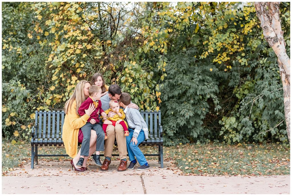 a family of 6 plays together on a bench at baker park
